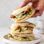 stack of meal prep breakfast sandwiches with the top one being grabbed off.