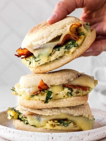 stack of meal prep breakfast sandwiches with the top one being grabbed off.