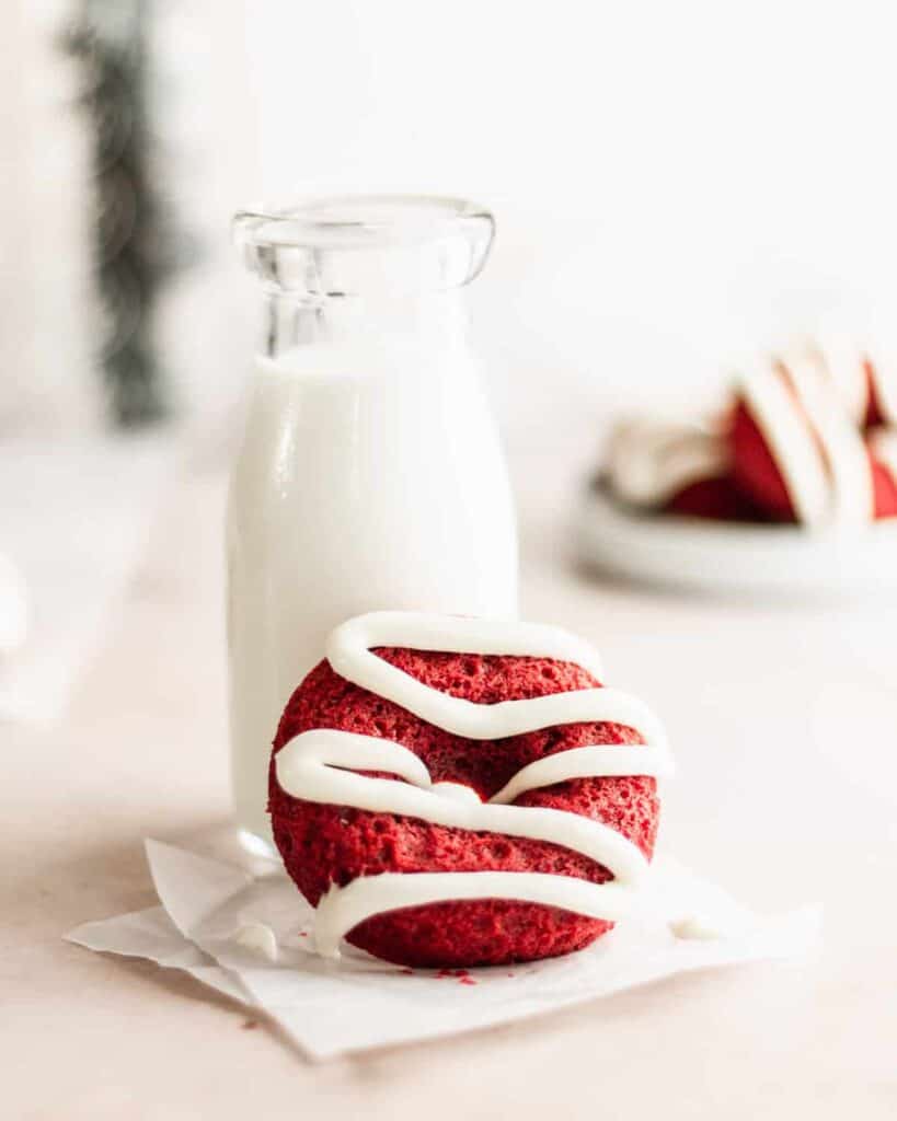 red velvet donut iced with cream cheese frosting with a glass of milk