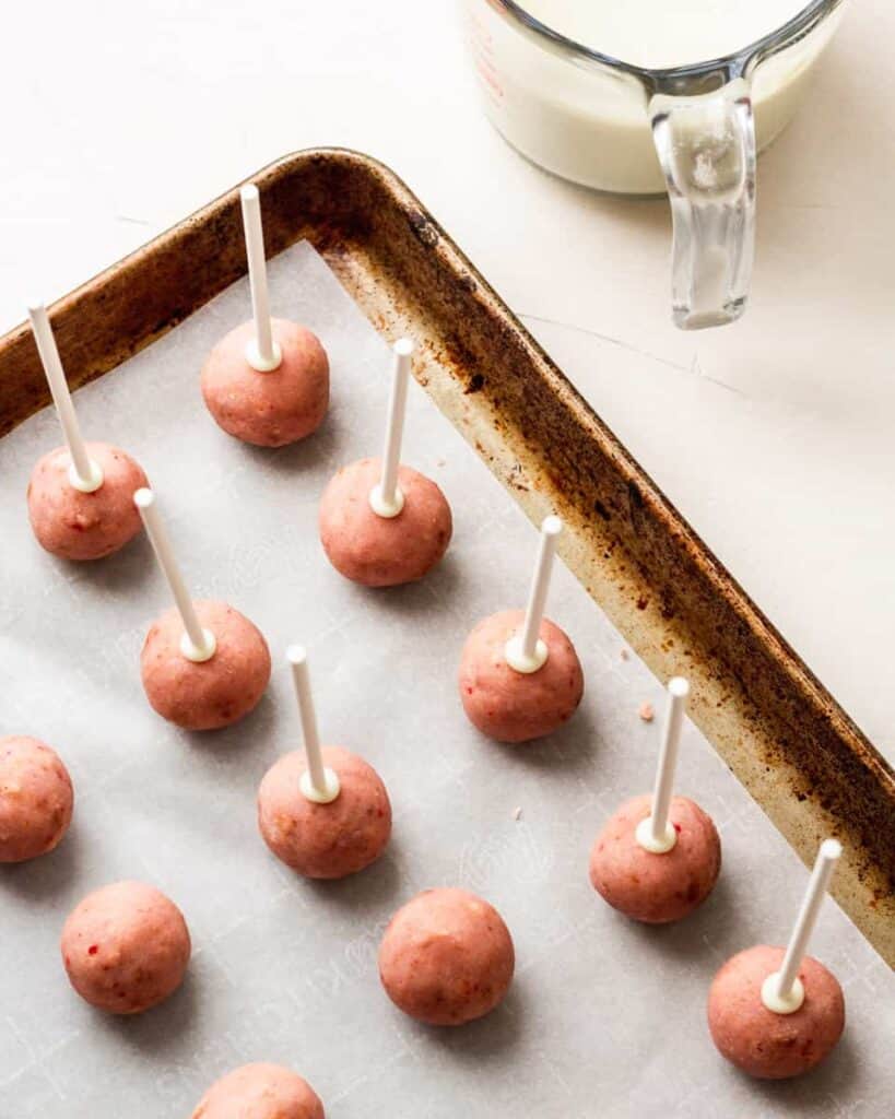 lollipop sticks are dipped in chocolate and pressed into cake balls to keep them from falling off