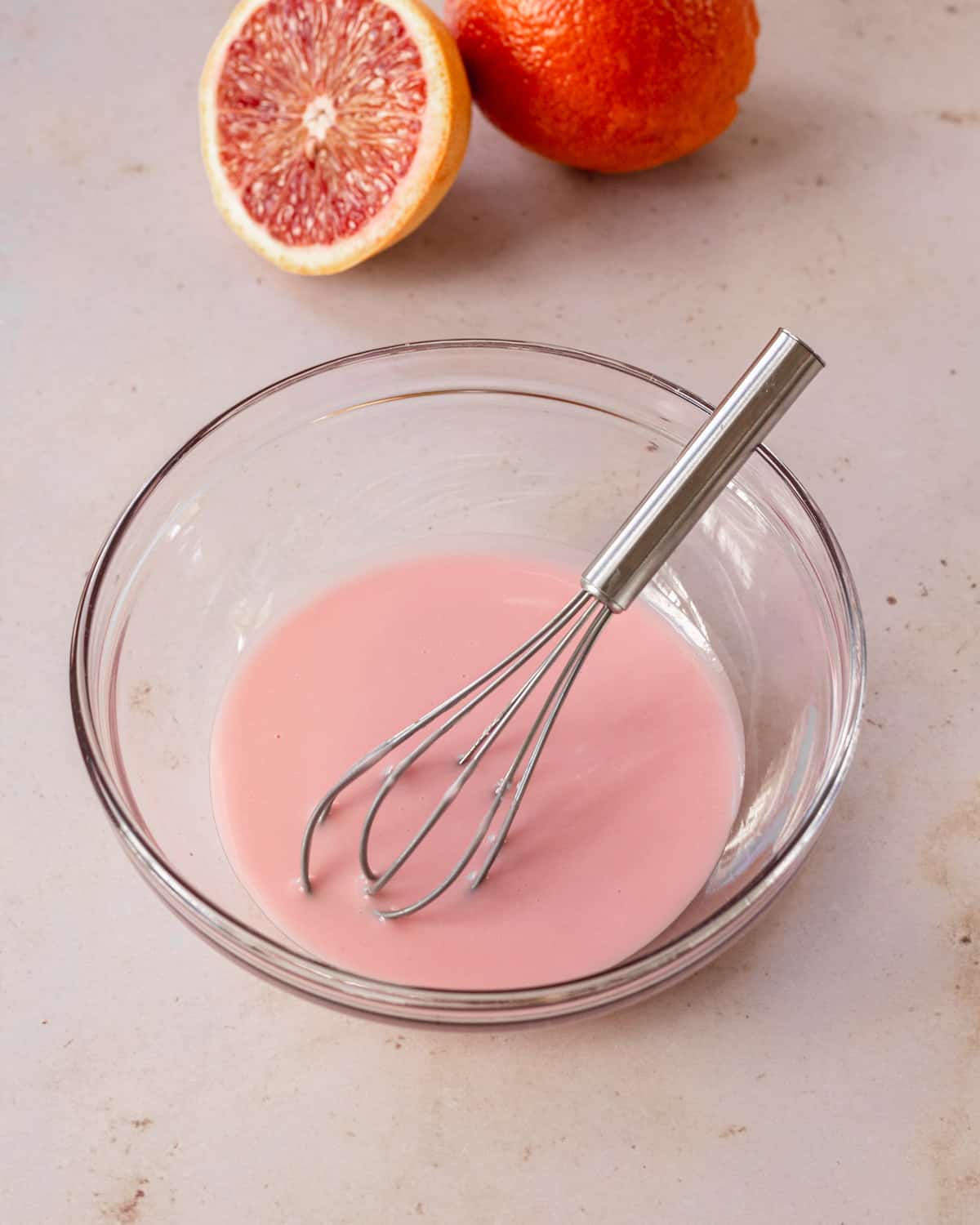 small bowl with whisk with bright pink blood orange glaze 