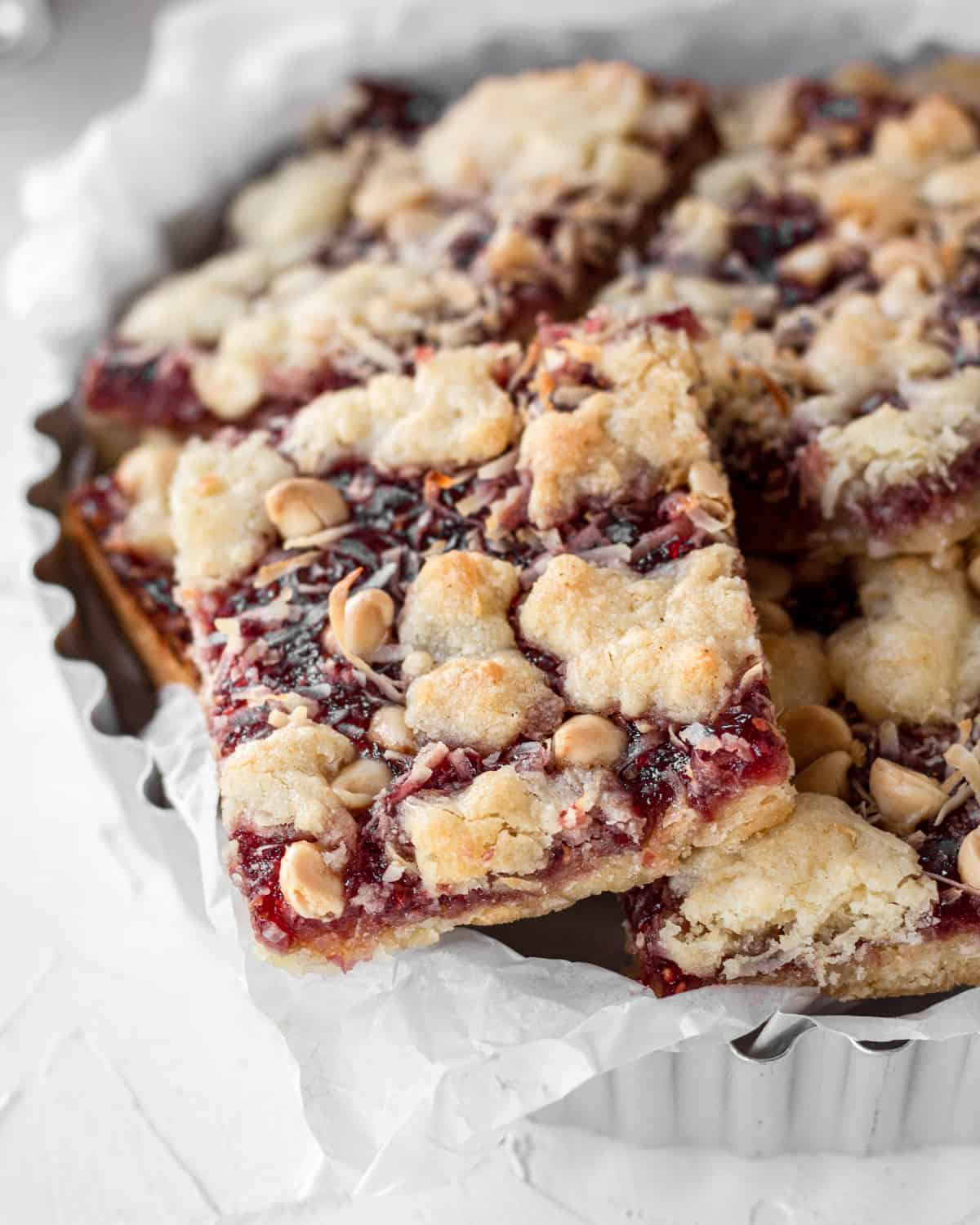 a bowl filled with raspberry crumble bars stacked on top of one another. 
