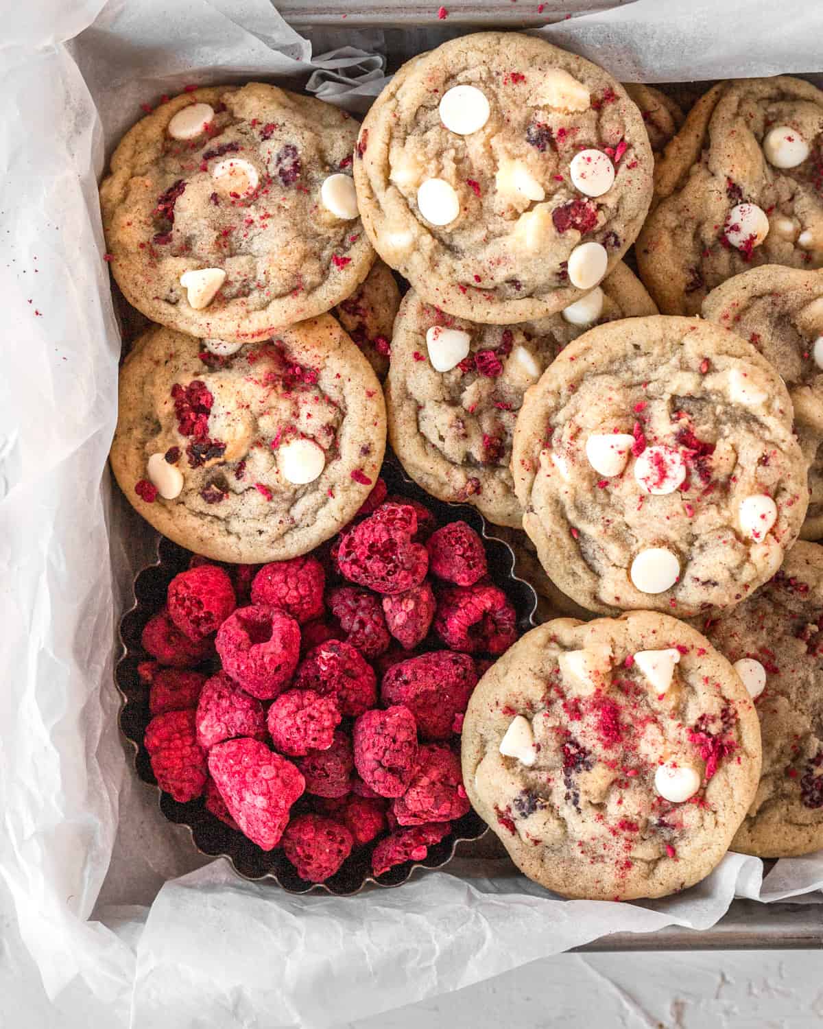a pan lined with parchment paper and filled with cookies and freeze-dried raspberries