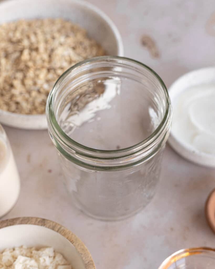 clear jar with high-protein overnight oats ingredients on the sides before mixing. 