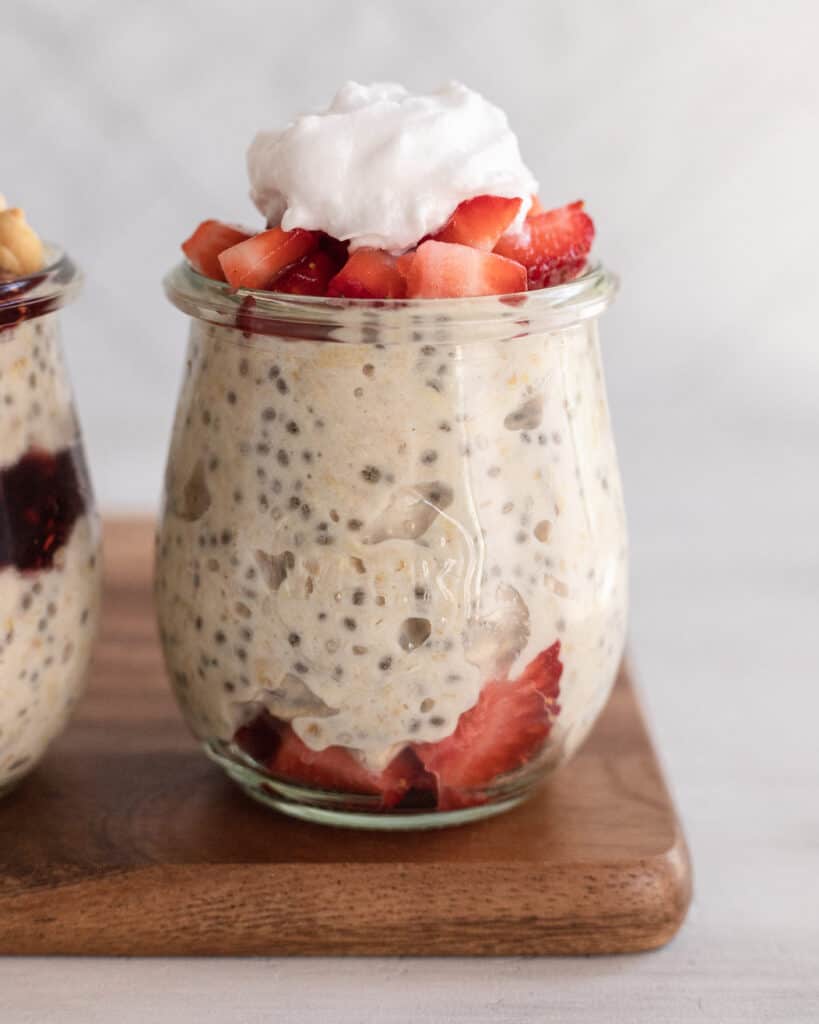 clear jar with overnight oats, strawberries, and whipped cream
