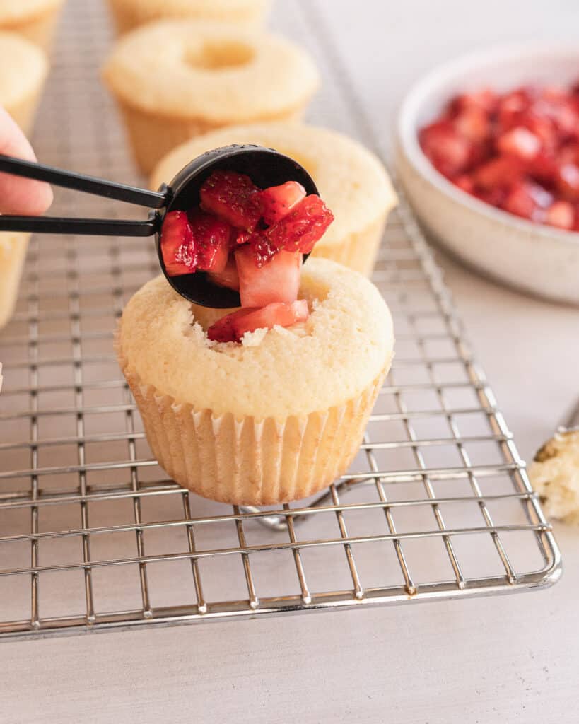 filling the cupcakes with the diced strawberries