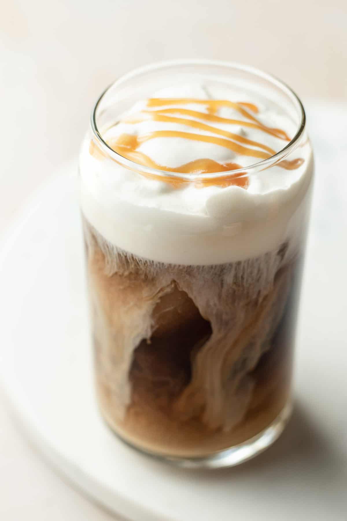 cold brew in a clear glass with cold foam on top and caramel drizzle