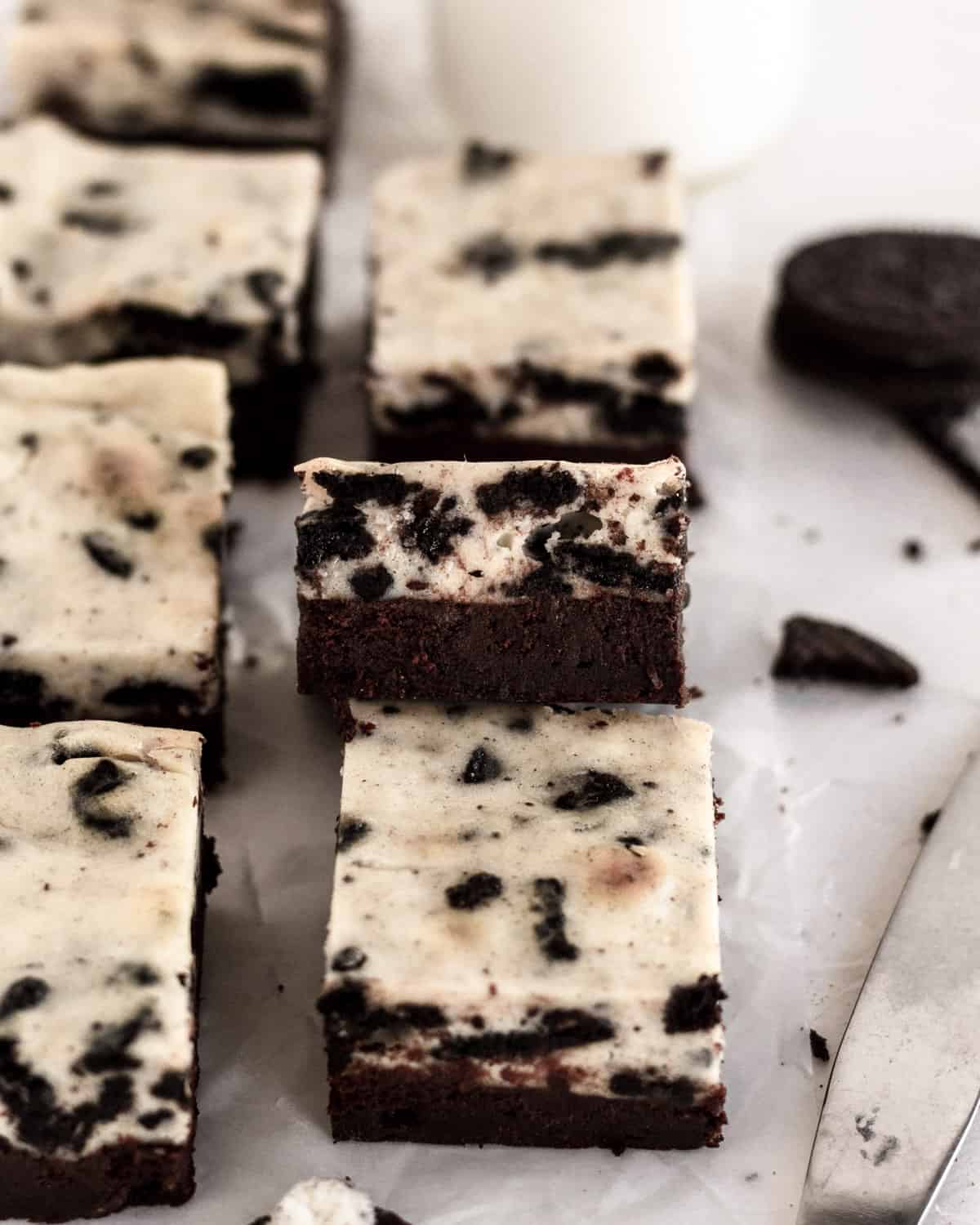 brownie squares on parchment paper with one propped up so you can see the layers. 