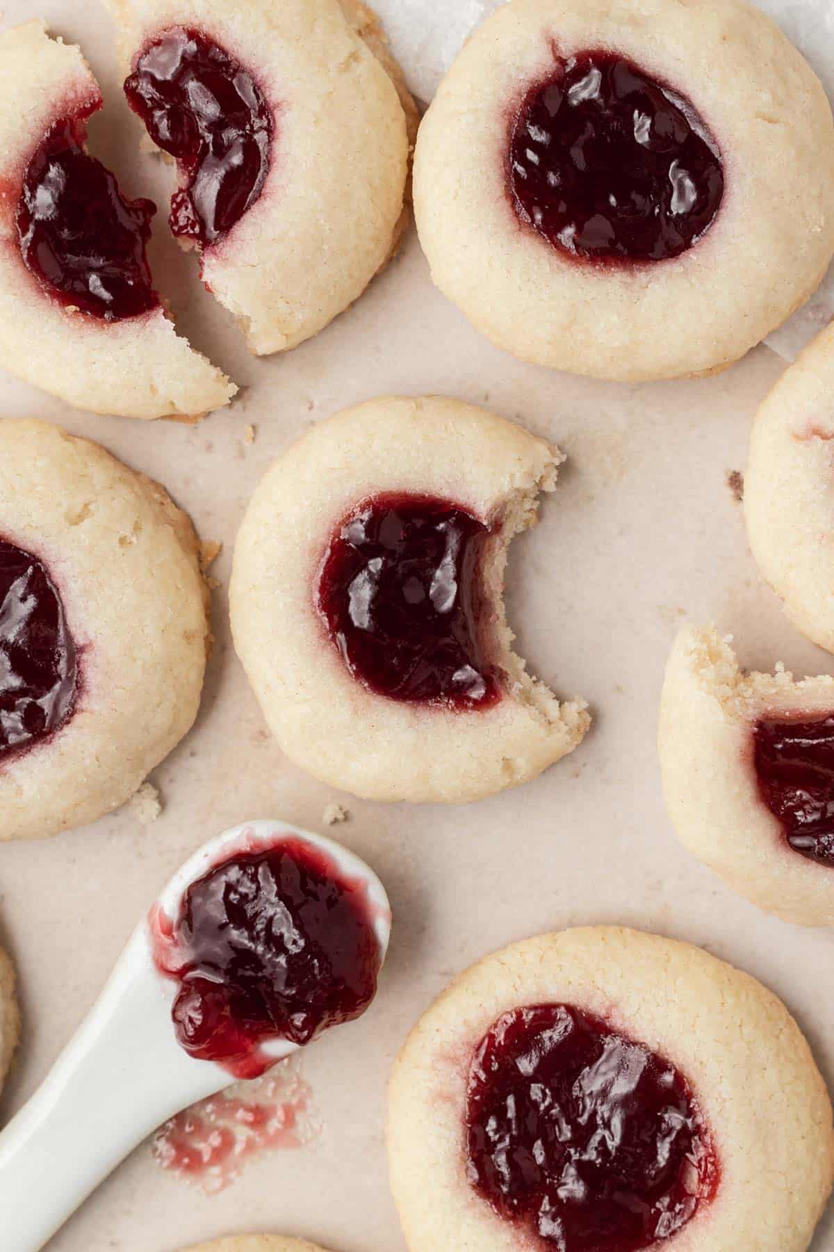 overhead view of raspberry thumbprints with bites taken out and a spoonful of jam