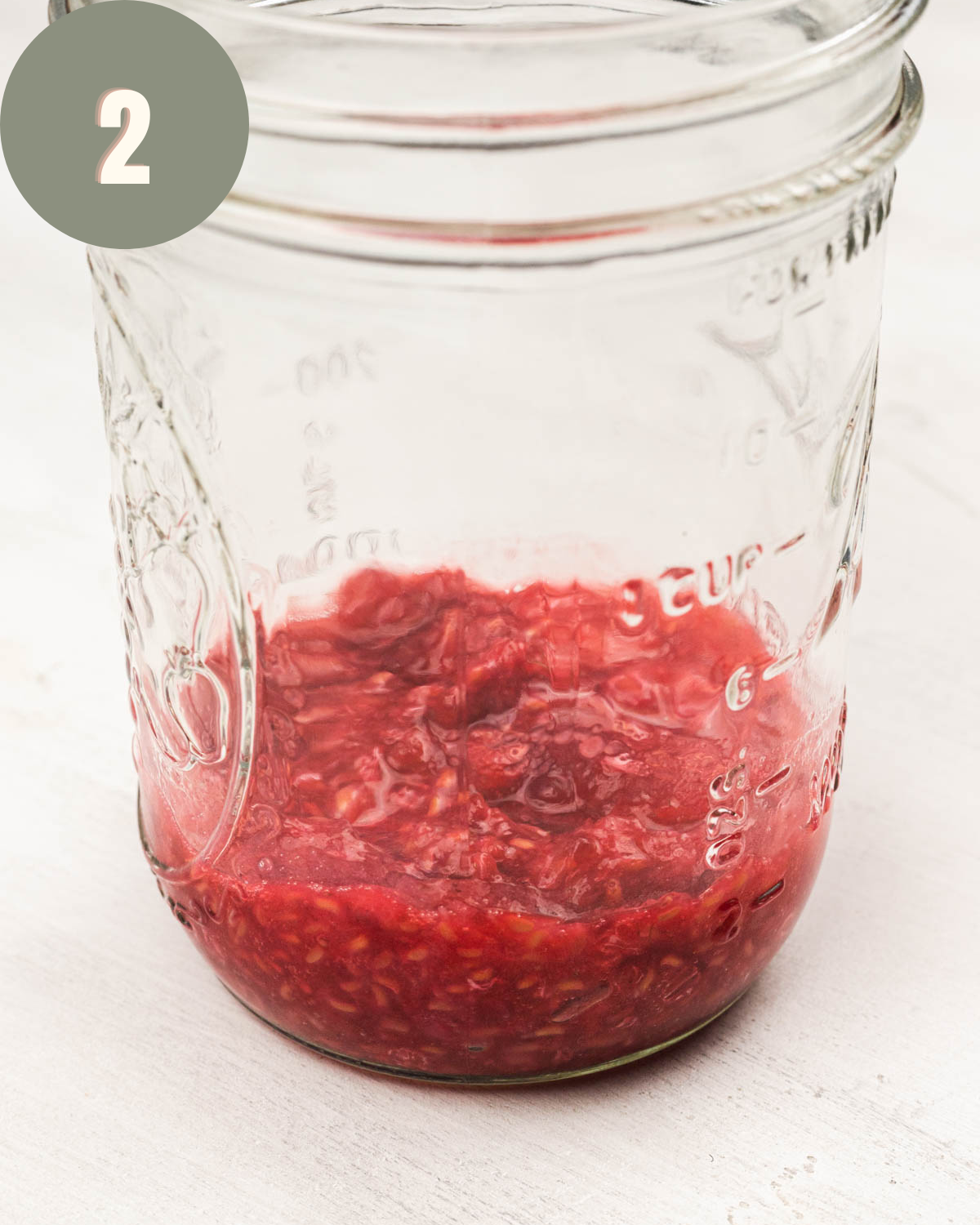 raspberries mashed on the bottom of a mason jar
