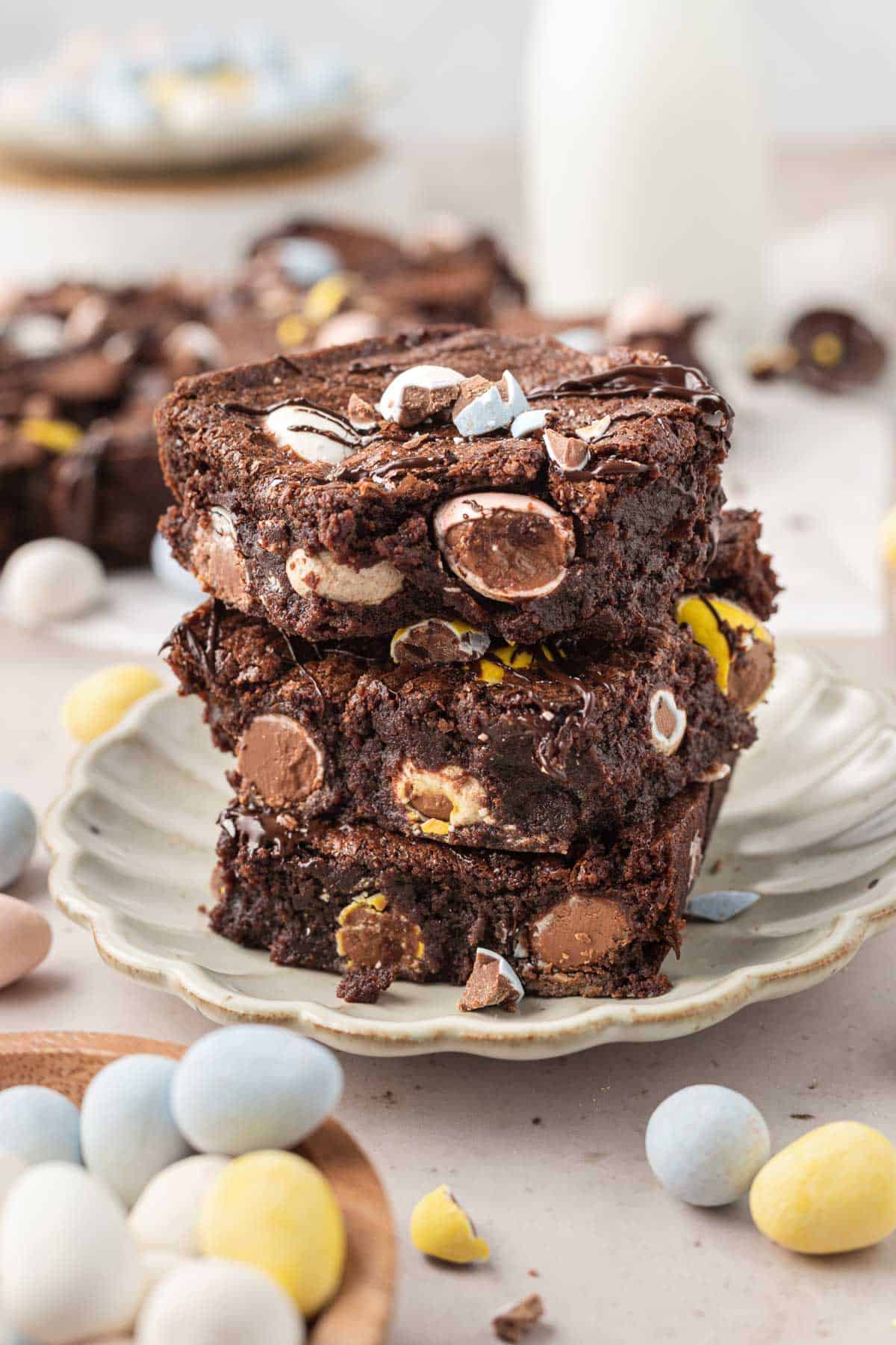 a stack of 3 brownies on a bite plate with mini eggs around it