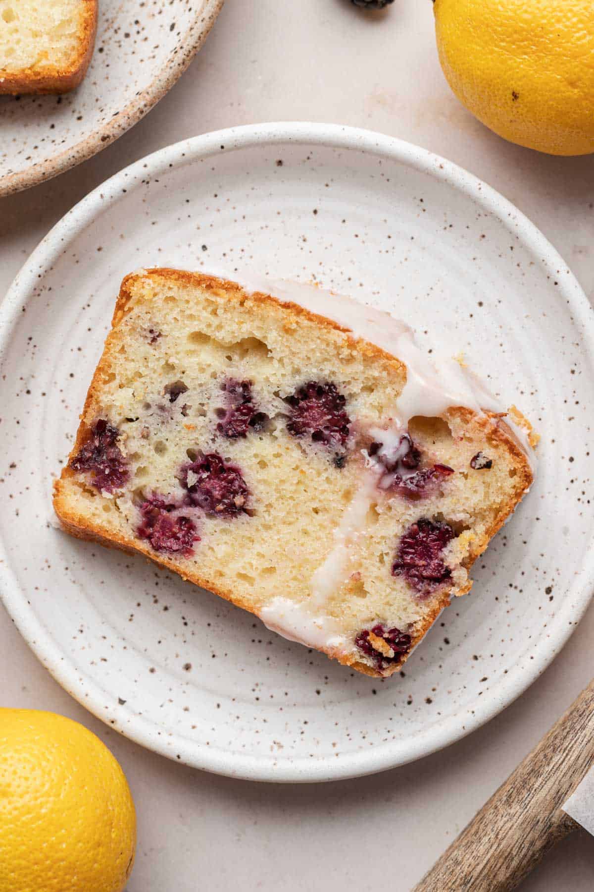slice of blackberry lemon loaf sitting on a white plate 