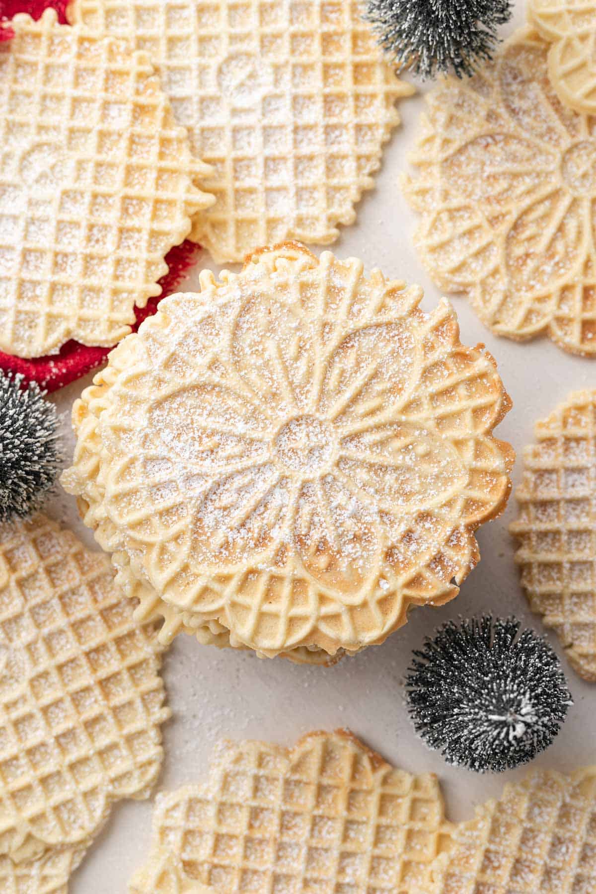 Stack of Pizzelle Cookies with anise on table, freshly dusted with powdered sugar.