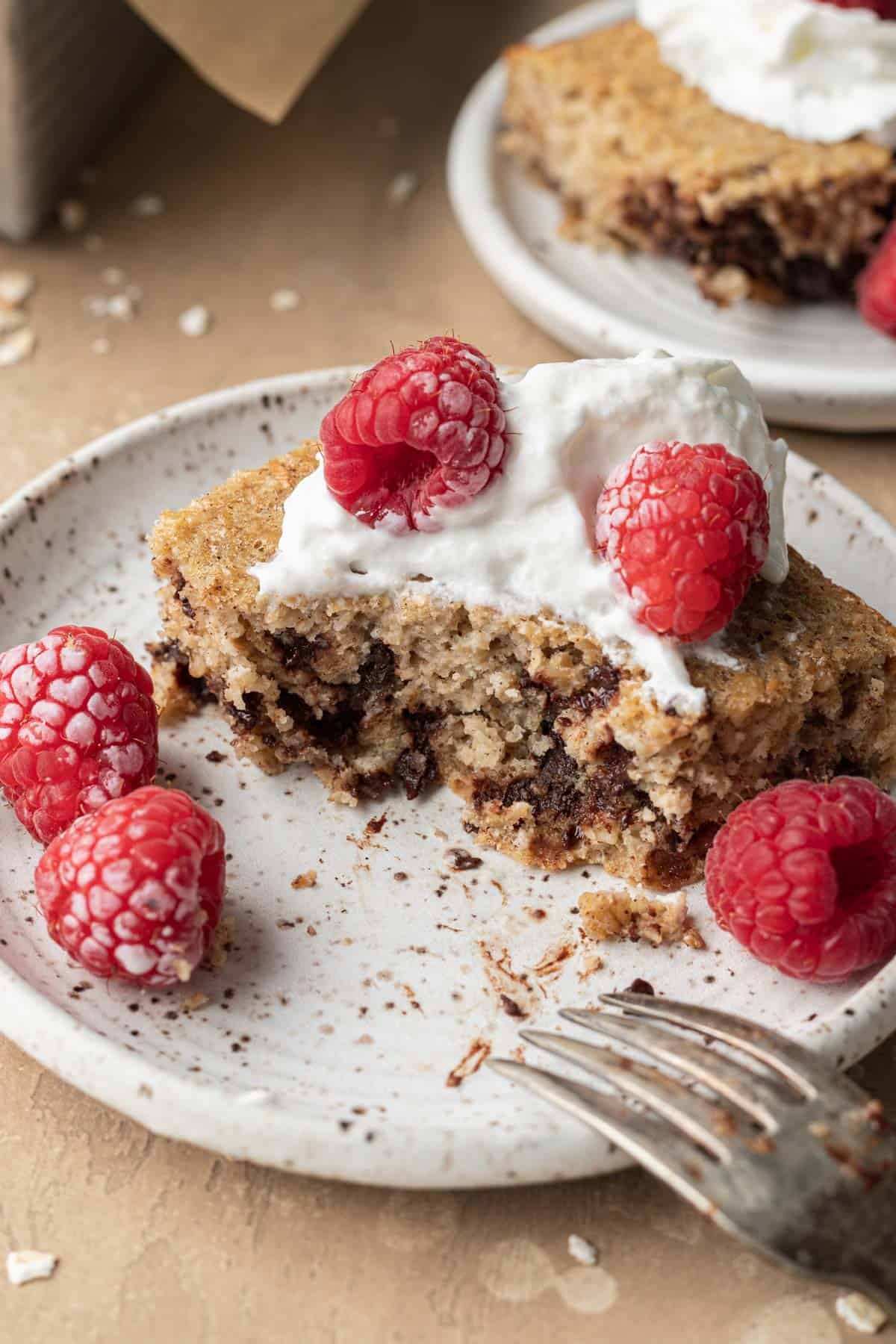 Fully cooked piece of Protein Baked Oats that has a bite taken out of it. Topped with whipped cream and raspberries!