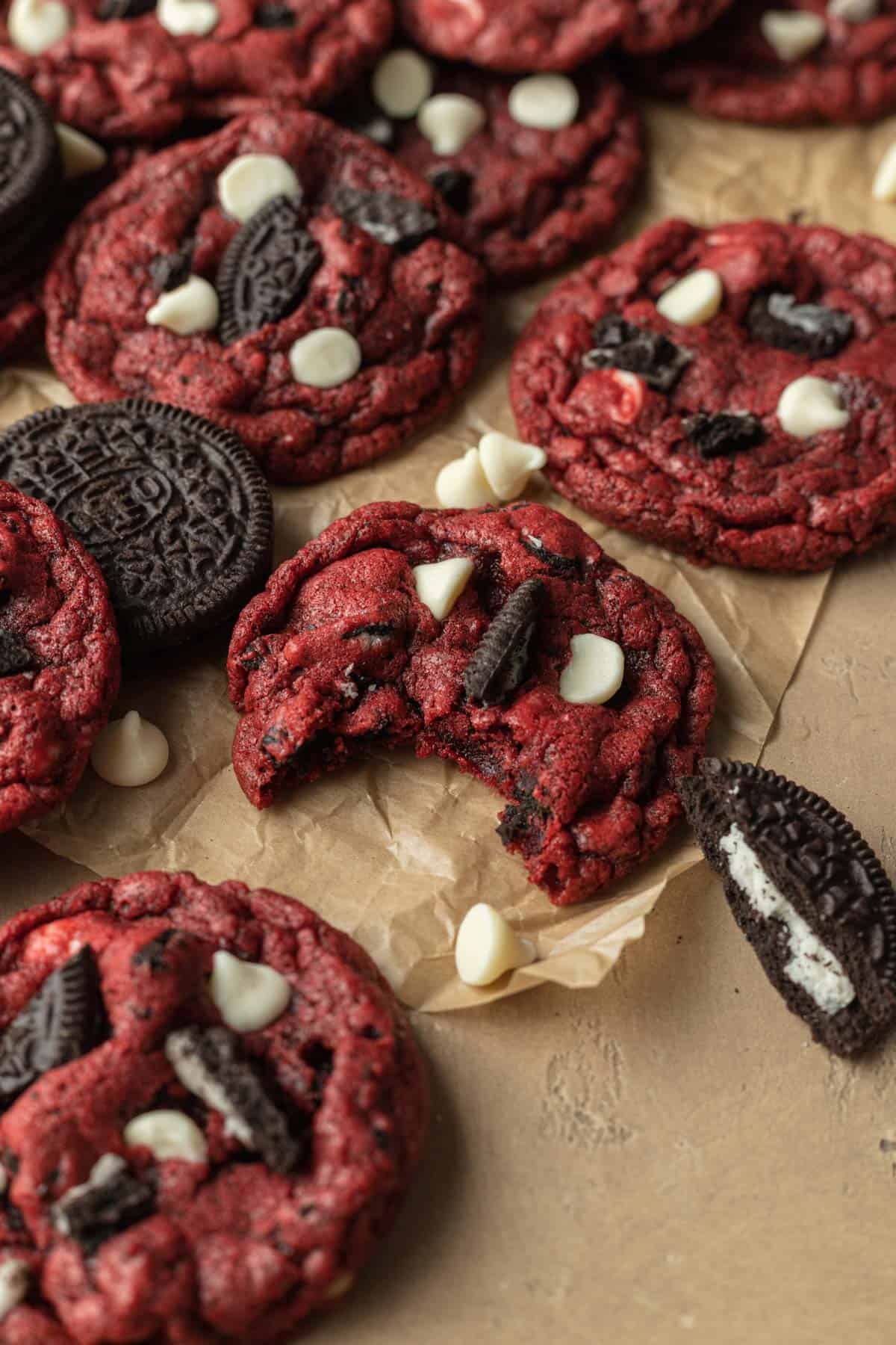 Ready to eat Red Velvet Oreo Cookies sitting on a sheet of parchment paper showing one cookie that recently had a bite taken out of it!