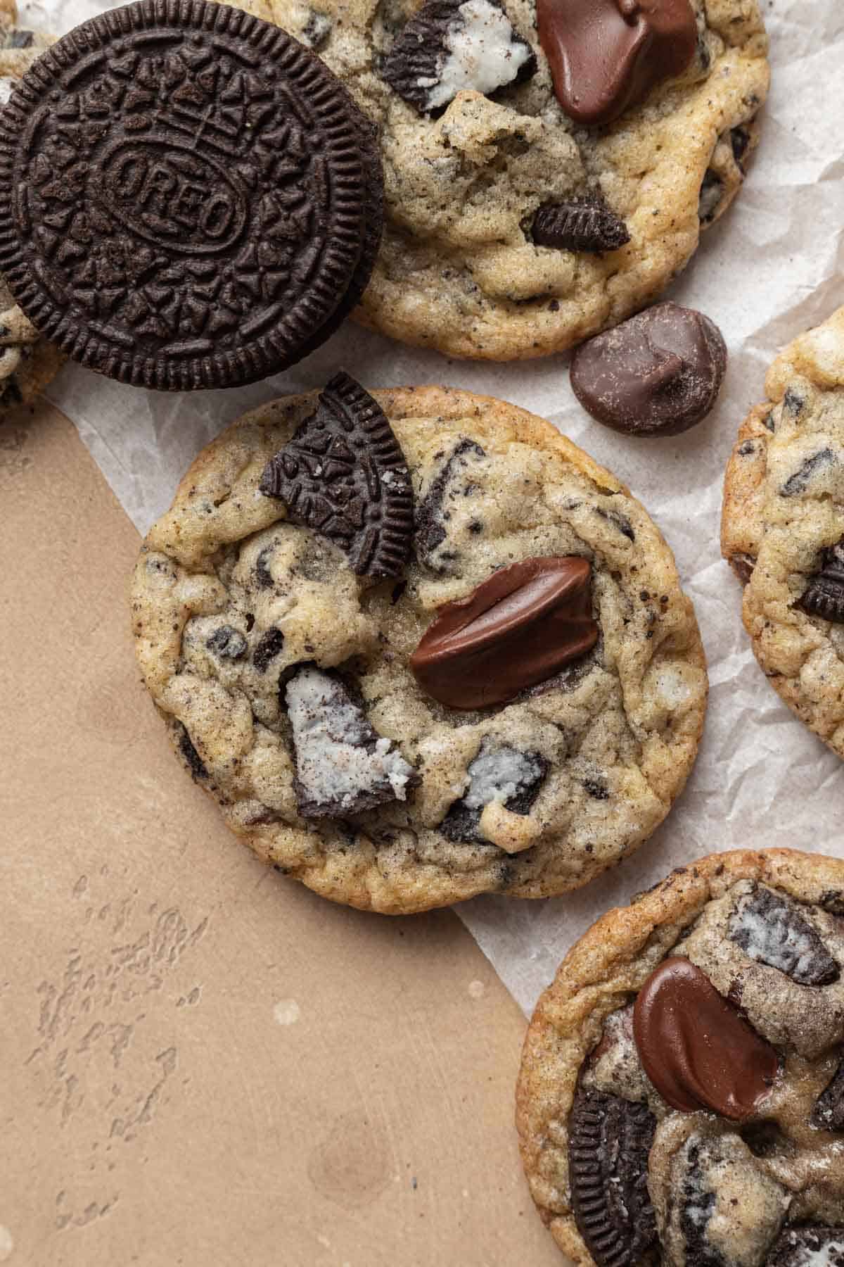 up close of an oreo chocolate chip cookie with gooey chocolate chip on top and an oreo next to it.