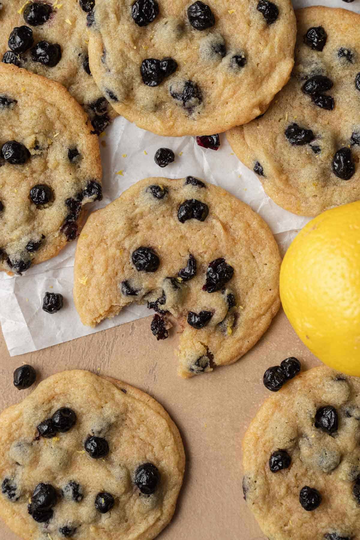 overhead view of cookies with one lemon blueberry cookie with a bite taken out of it. 