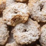 Fresh batch of crumb donuts piled on top of one another. Donut on the top has a bite out of it!