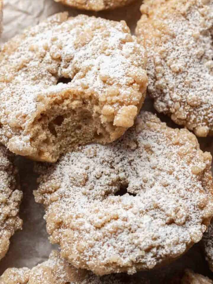 Fresh batch of crumb donuts piled on top of one another. Donut on the top has a bite out of it!