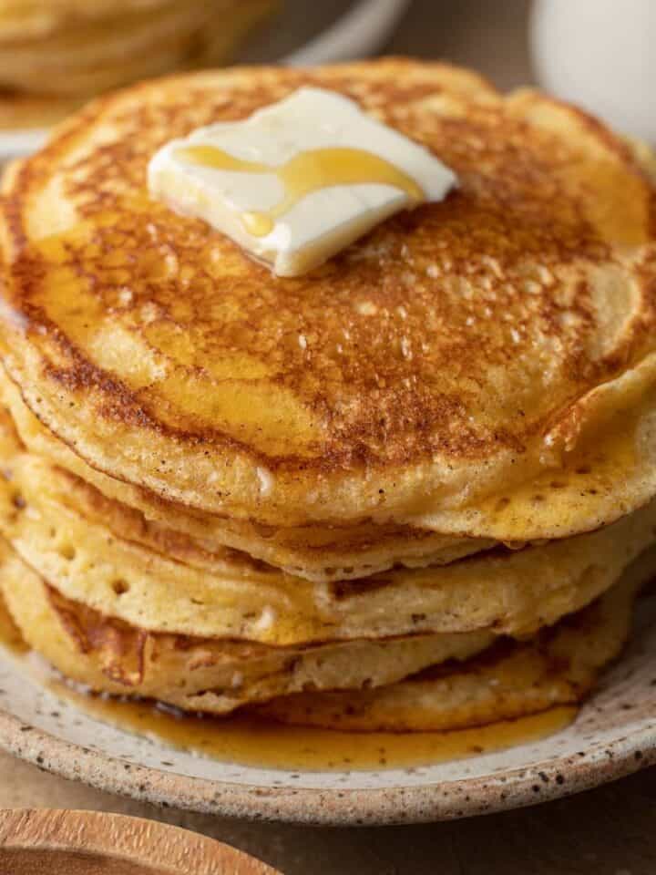 Fresh stack of cornbread pancakes plated with butter and syrup on top.