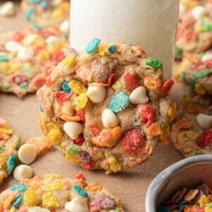 fruity pebble cookie propped up against a glass of milk surrounded by other cookies