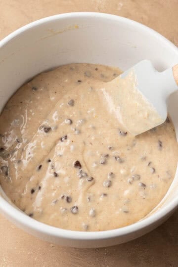 muffin batter fully mixed with mini chocolate chips added, in a white bowl.
