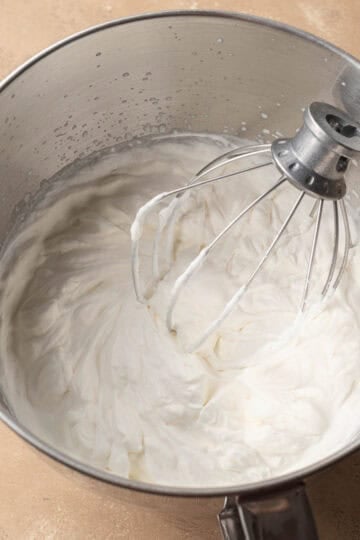 whipped cream whipped in a silver bowl with a whisk.