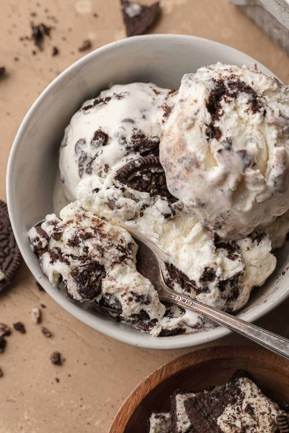 spoon taking a scoop out of oreo ice cream in a white bowl.