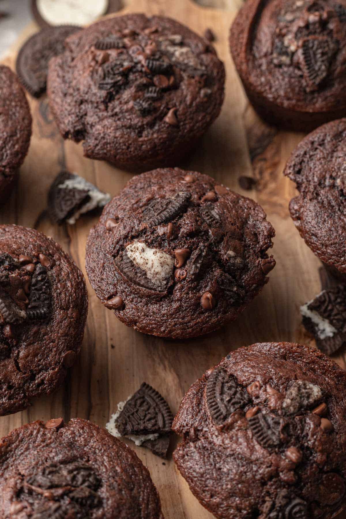 Oreo muffins laying out on a wooden cutting board that are ready to be eaten.
