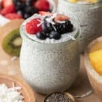 Chia seed breakfast bowl in a glass jar that is topped with mixed berries and coconut flakes.