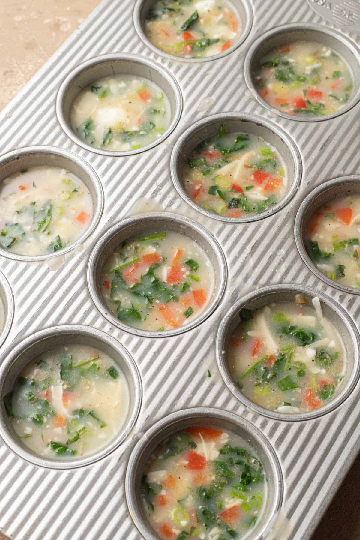 Egg whites added into metal muffin tins and ready to be put in the oven.