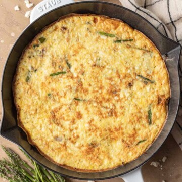 Fully baked asparagus feta frittata in a cast iron skillet.