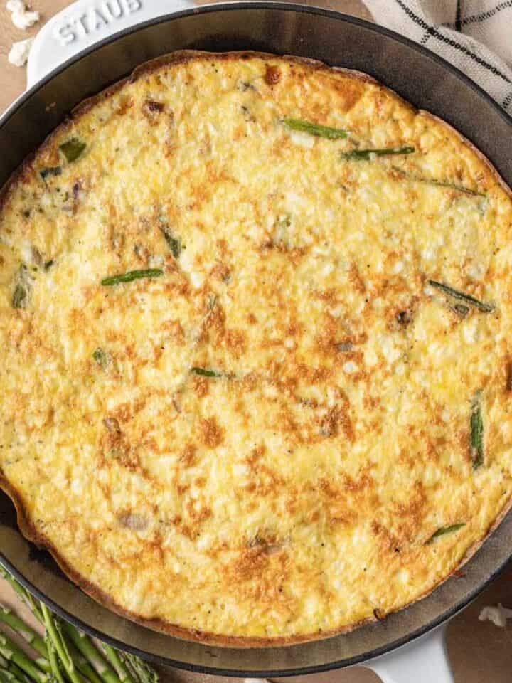 Fully baked asparagus feta frittata in a cast iron skillet.