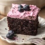 square of chocolate blueberry cake on a white scalloped plate