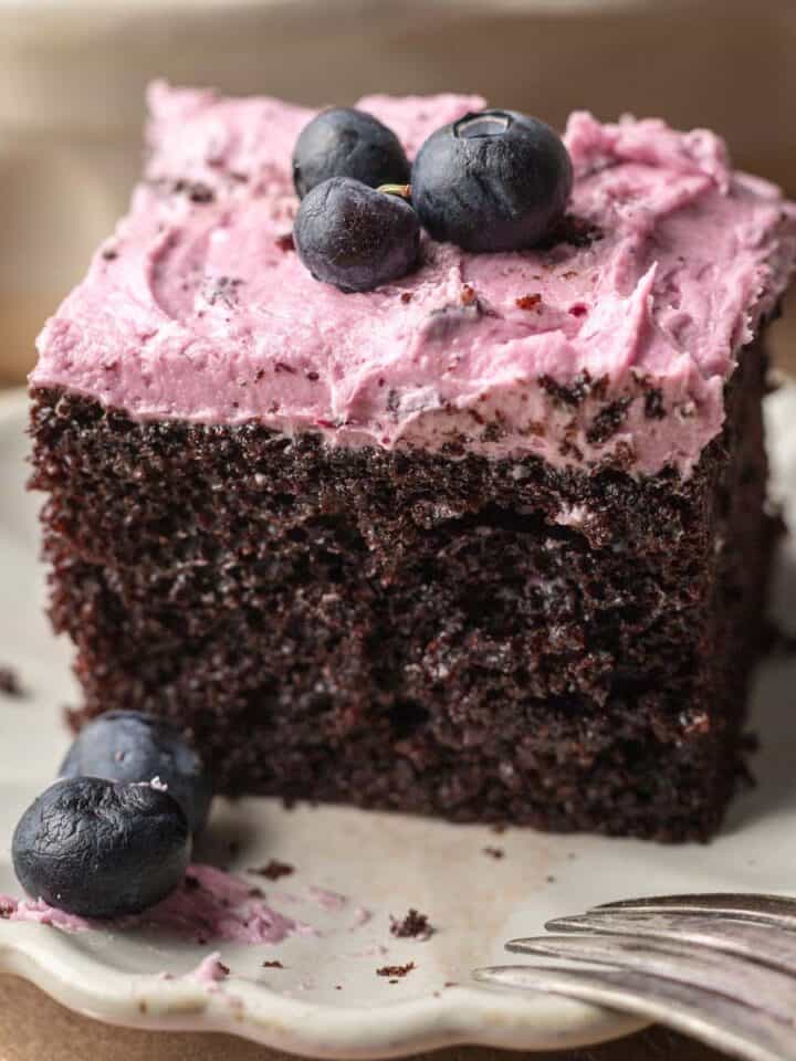 square of chocolate blueberry cake on a white scalloped plate