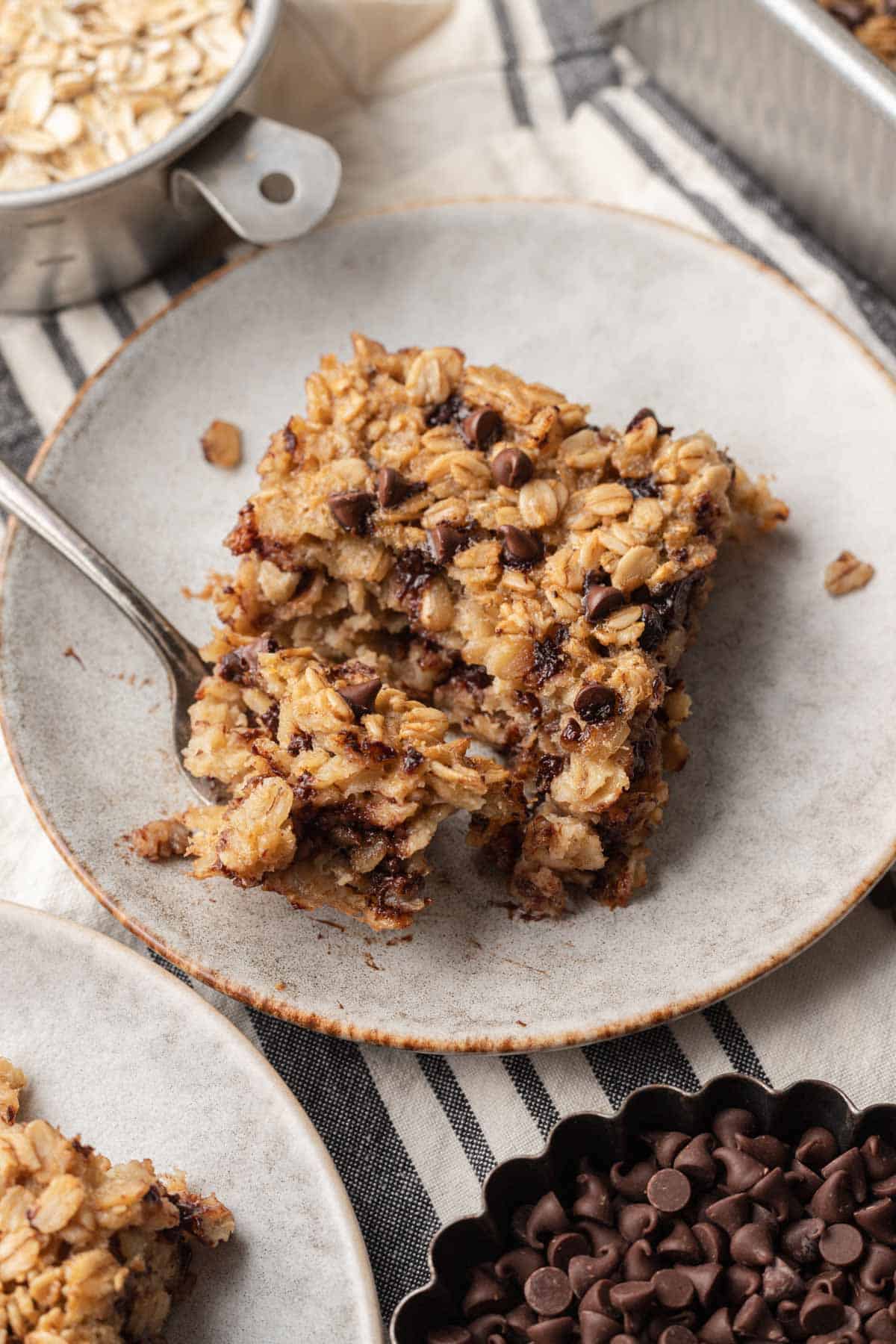 A slice of chocolate chip baked oatmeal on a plate with a fork.