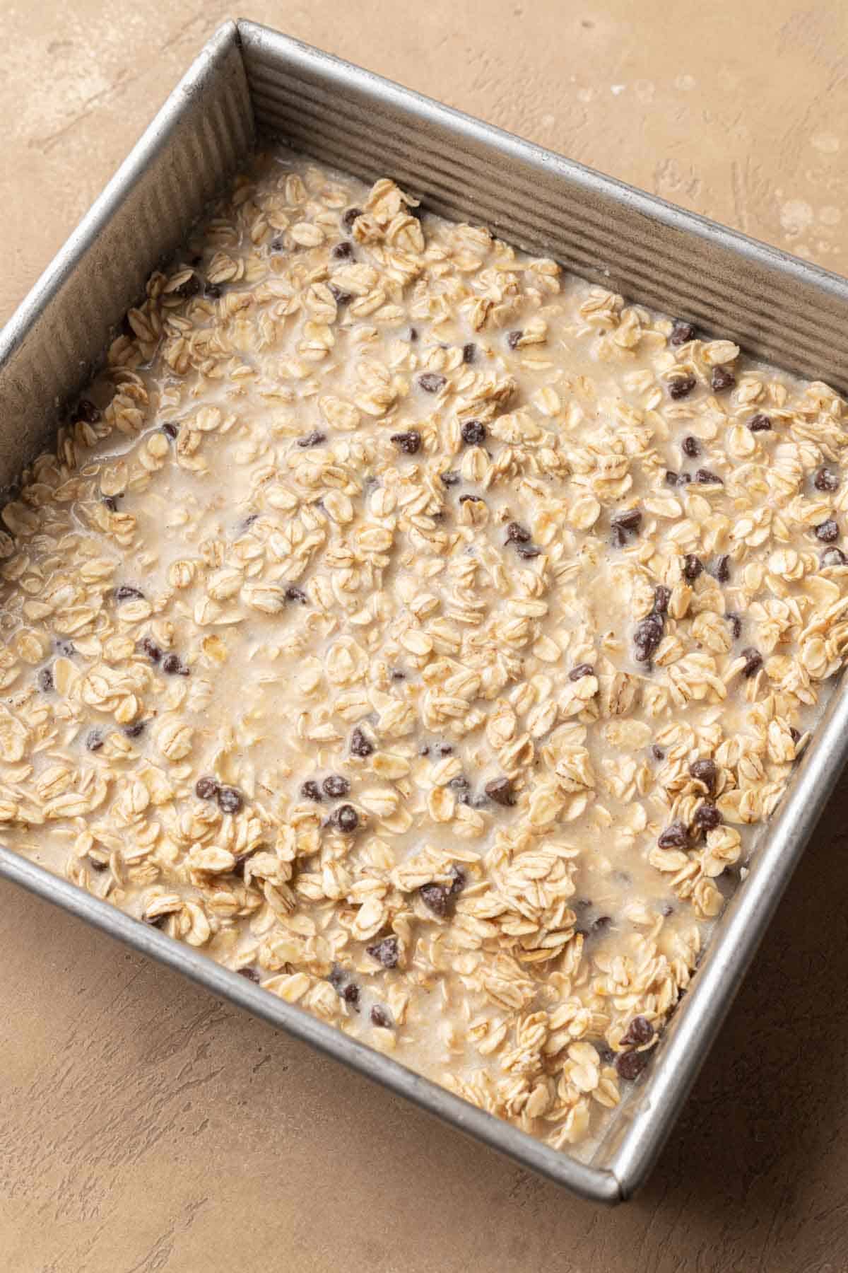 Chocolate chip oatmeal batter in tin baking pan.