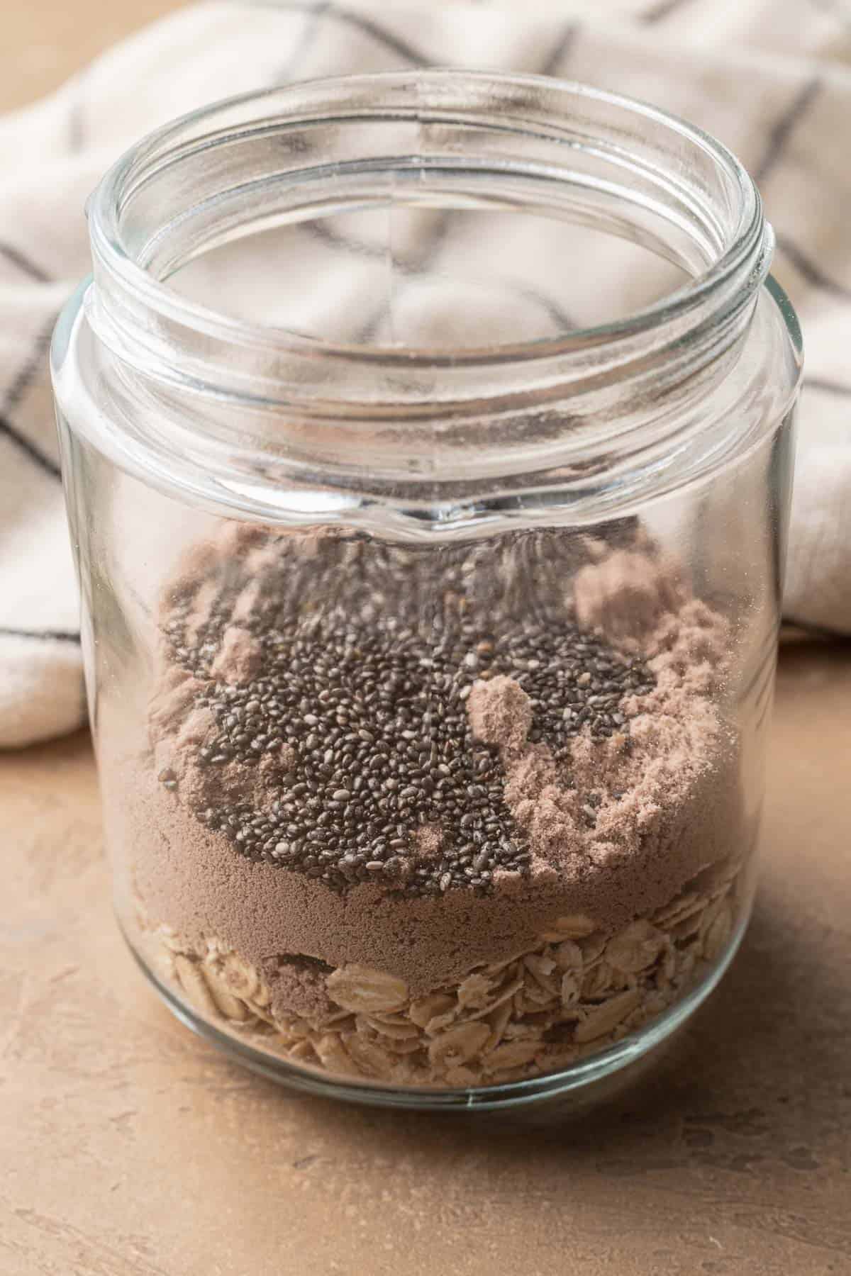 Dry ingredients for chocolate protein overnight oats in a clear mason jar.