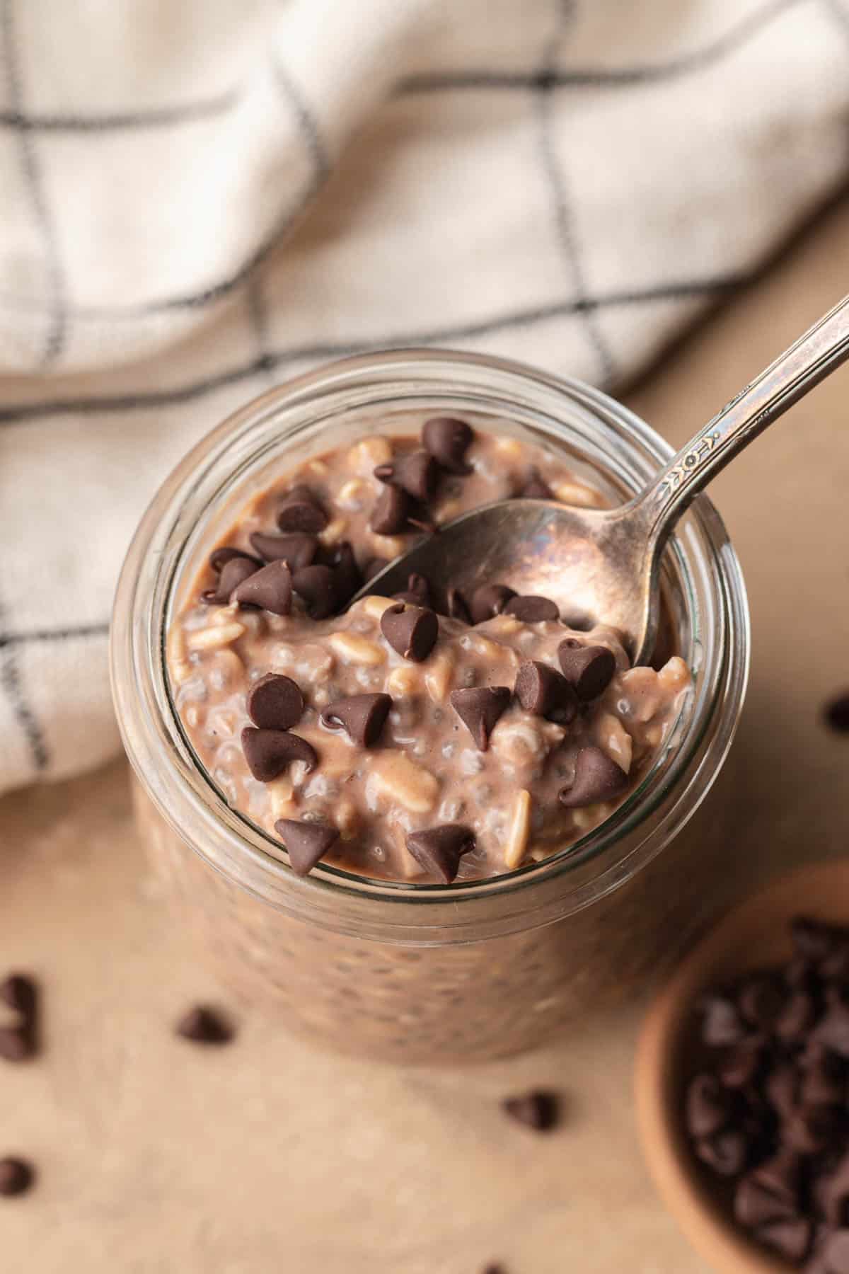 Birds eye view of a jar of chocolate protein overnight oats with chocolate chips sprinkled on top.