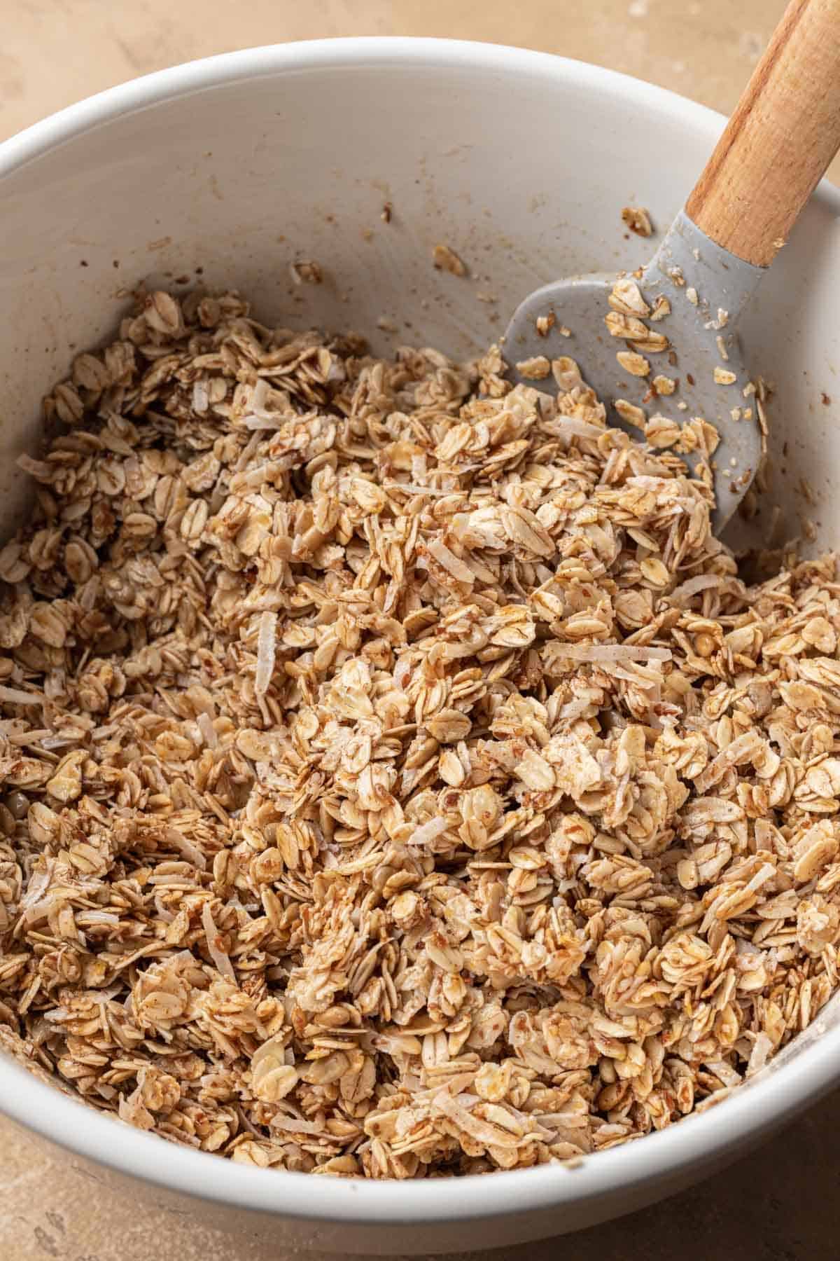 Dry and wet ingredients for homemade granola in a white mixing bowl.