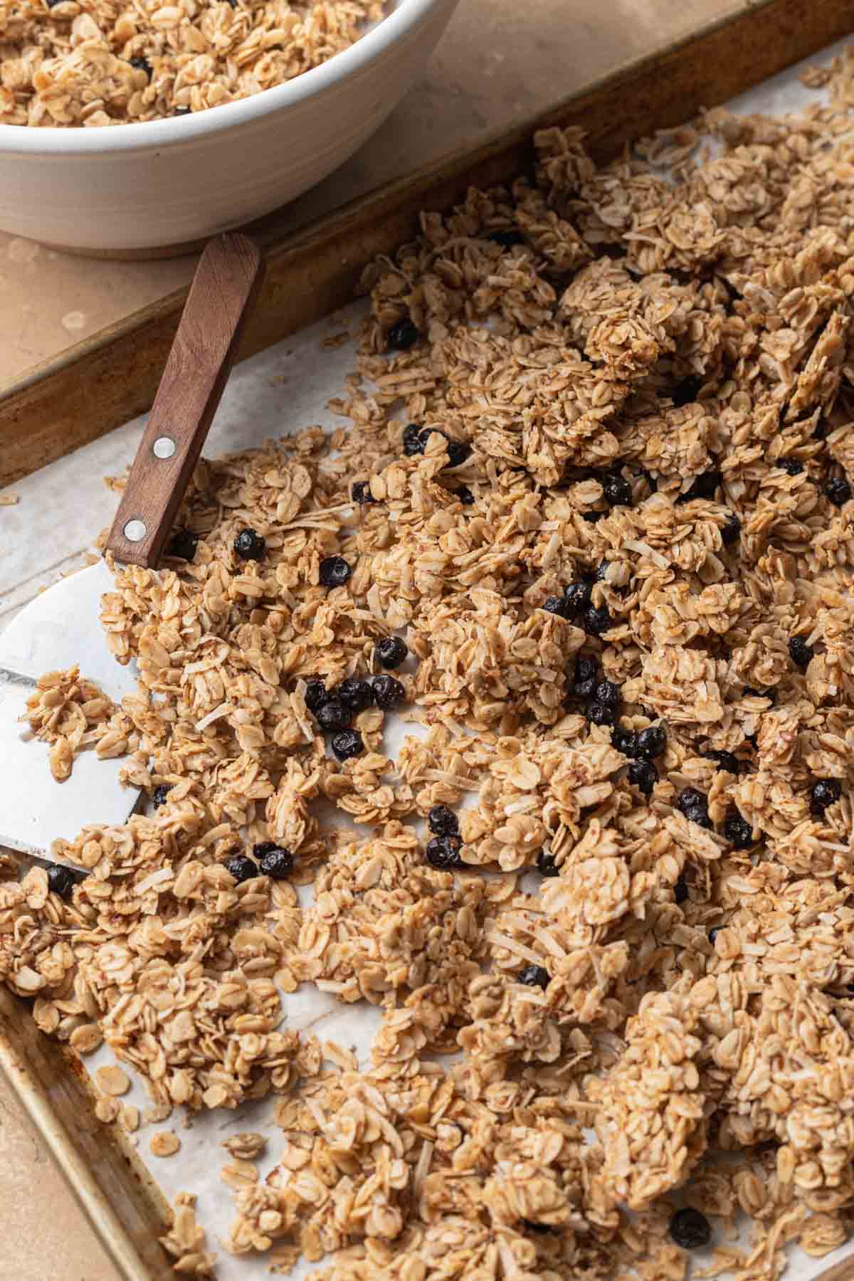 Fresh batch of homemade granola that is sitting on a baking sheet with parchment paper.
