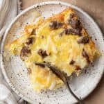 slice of dairy free breakfast casserole on a white plate with a fork taking a piece out of it.