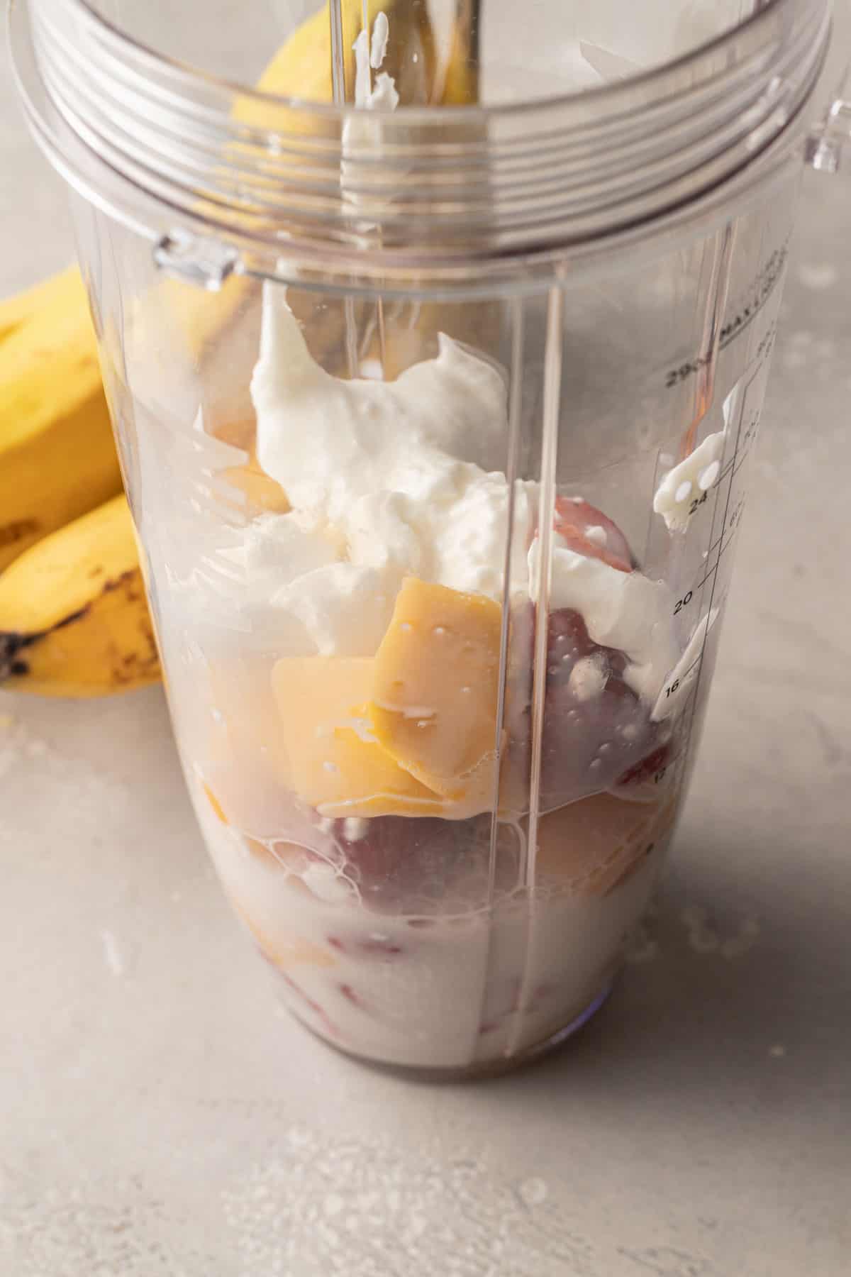 Mango strawberry banana smoothie ingredients in smoothie cup.