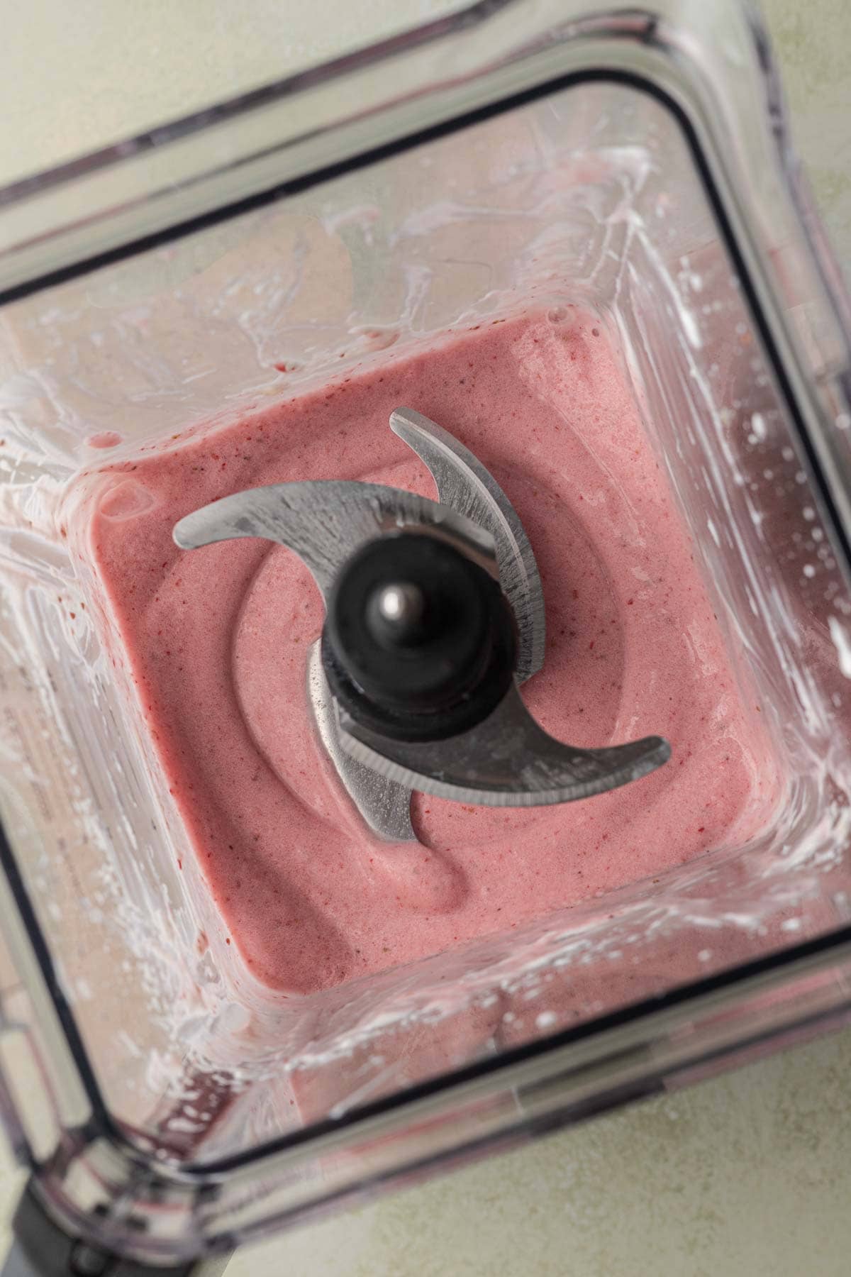 Blended ingredients for a strawberry smoothie bowl in clear blender.