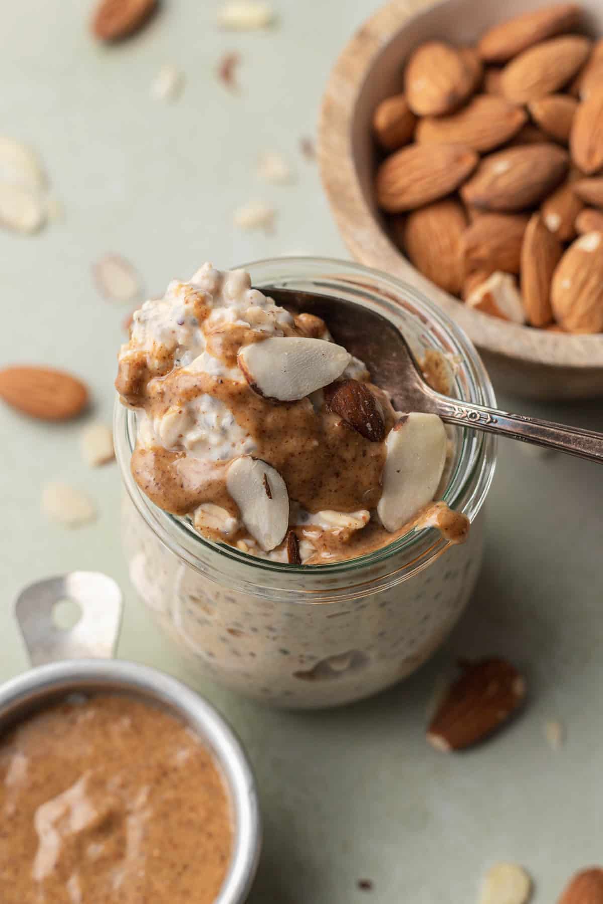 spoonful of almond butter overnight oats being taken from the glass jar.