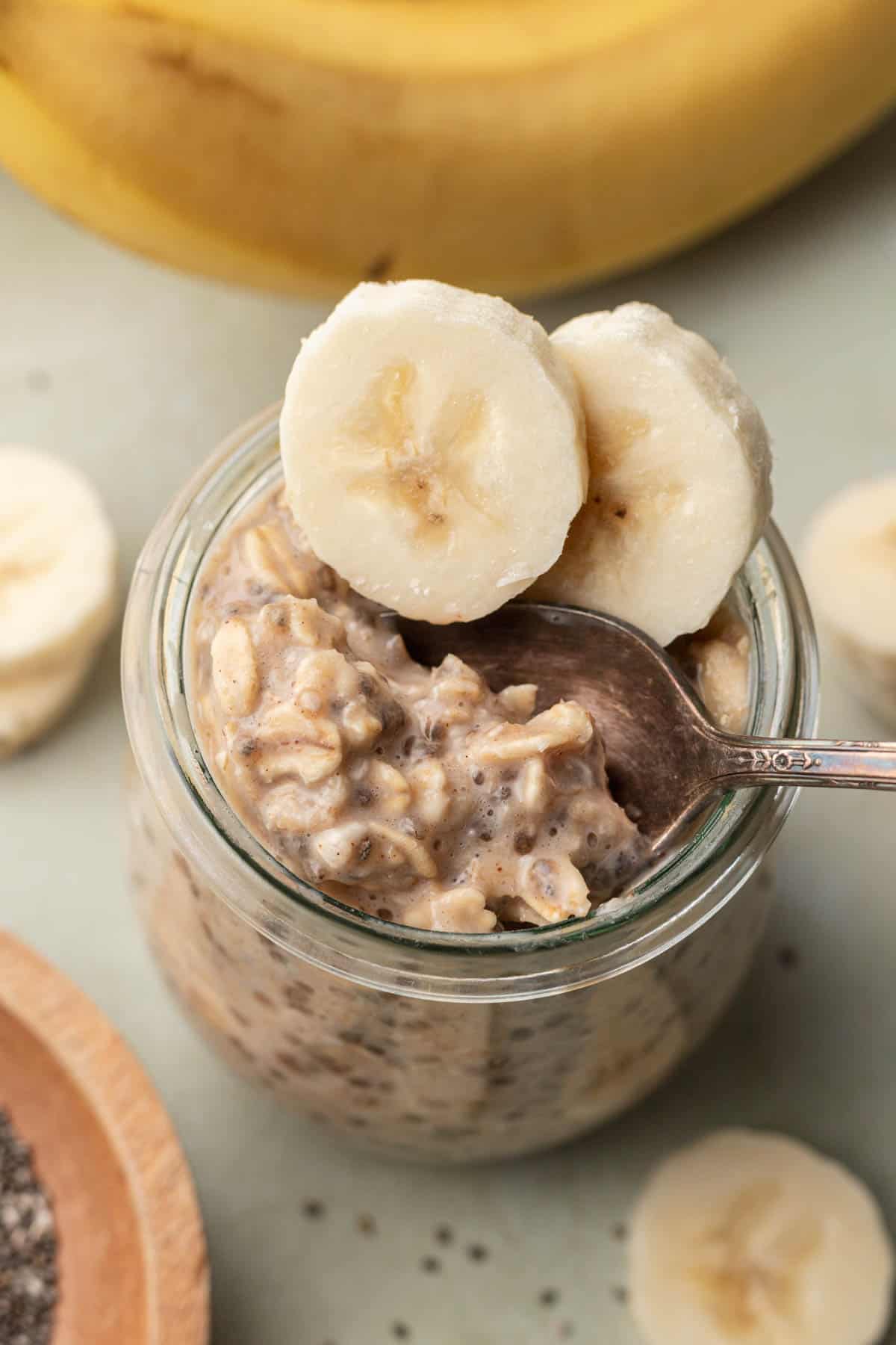 banana chia overnight oats in a glass jar with a spoon taking a scoop out of the top