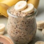 banana chia overnight oats in a glass jar with sliced bananas on top
