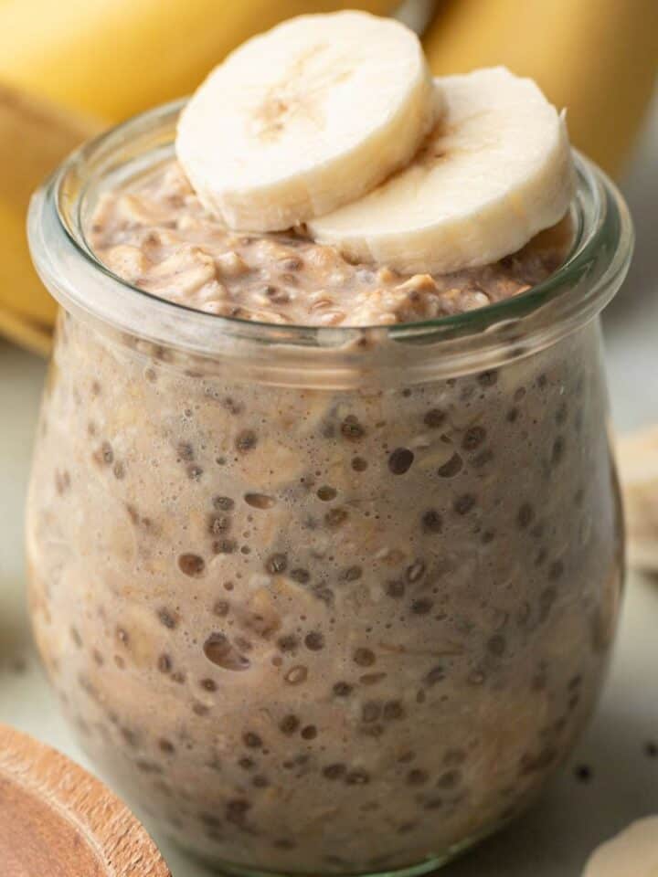 banana chia overnight oats in a glass jar with sliced bananas on top