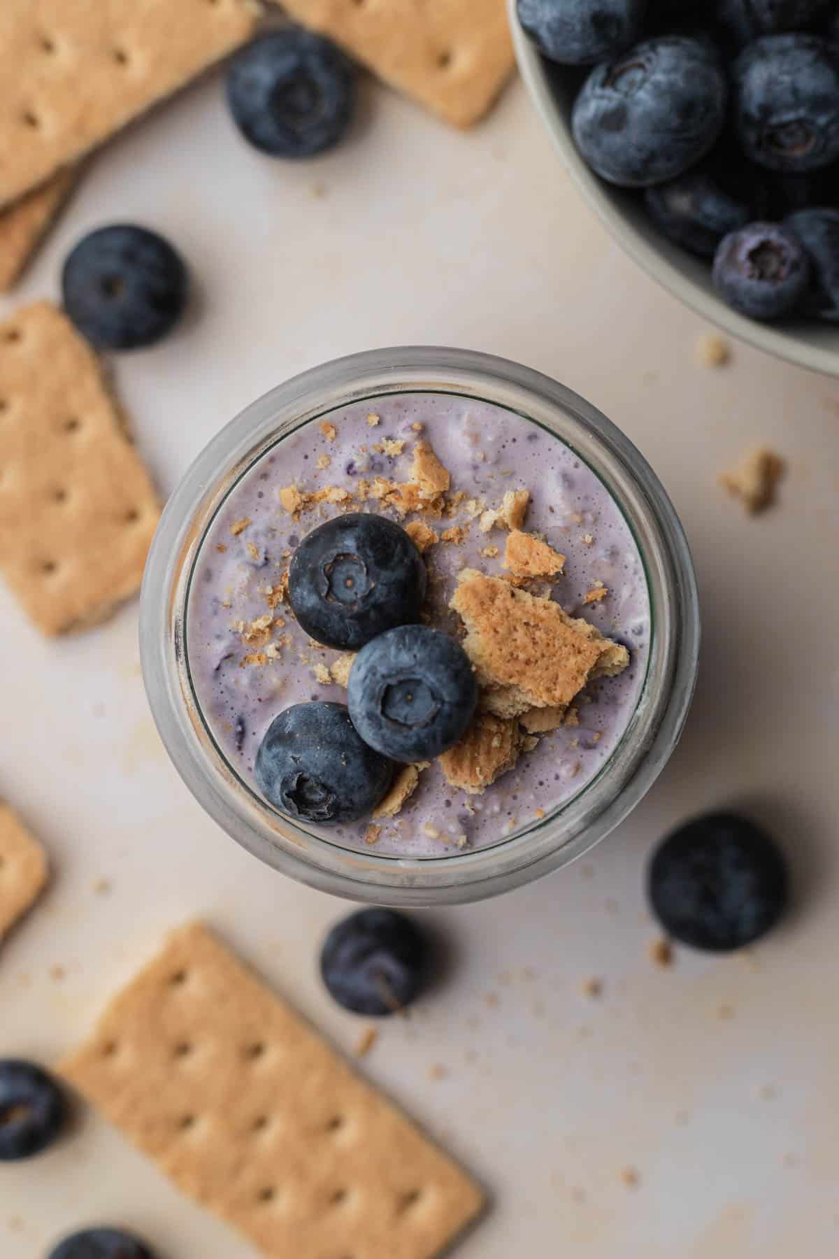 overhead view of blueberry cheesecake overnight oats topped with blueberries and graham crackers.