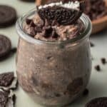 glass jar of oreo overnight oats with oreo on top.